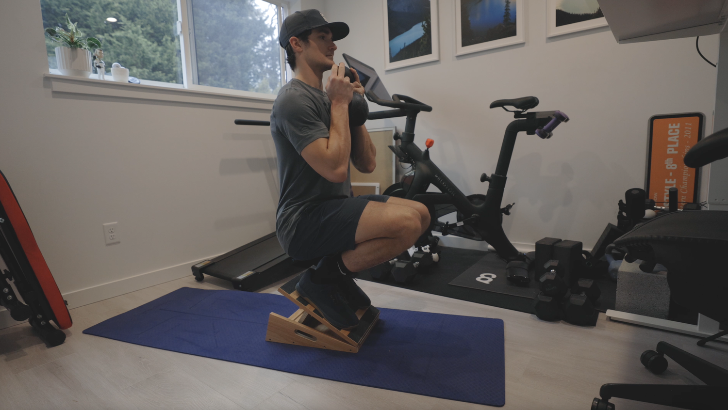 Deep goblet squat holding a kettlebell with both feet elevated on a wooden slant board