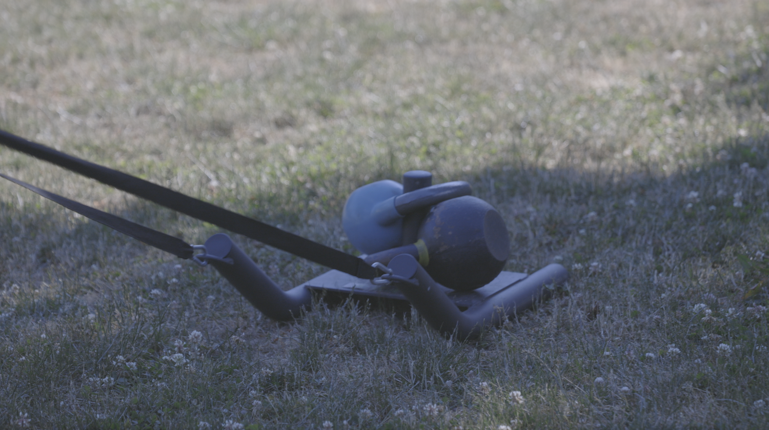 Close-up of a drag sled loaded with two kettlebells on the grass