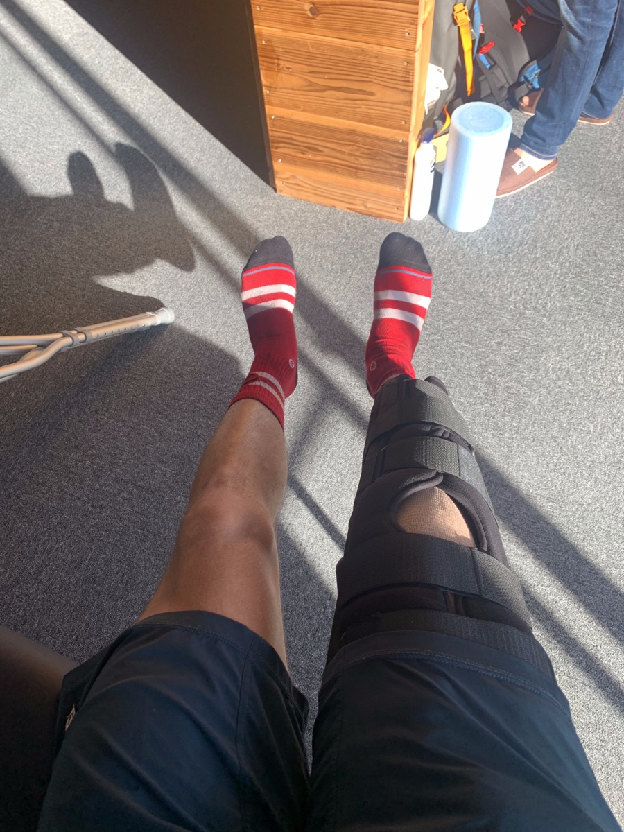 Looking down at Connor's braced right knee and a crutch on the floor, the day after tear number four in Japan